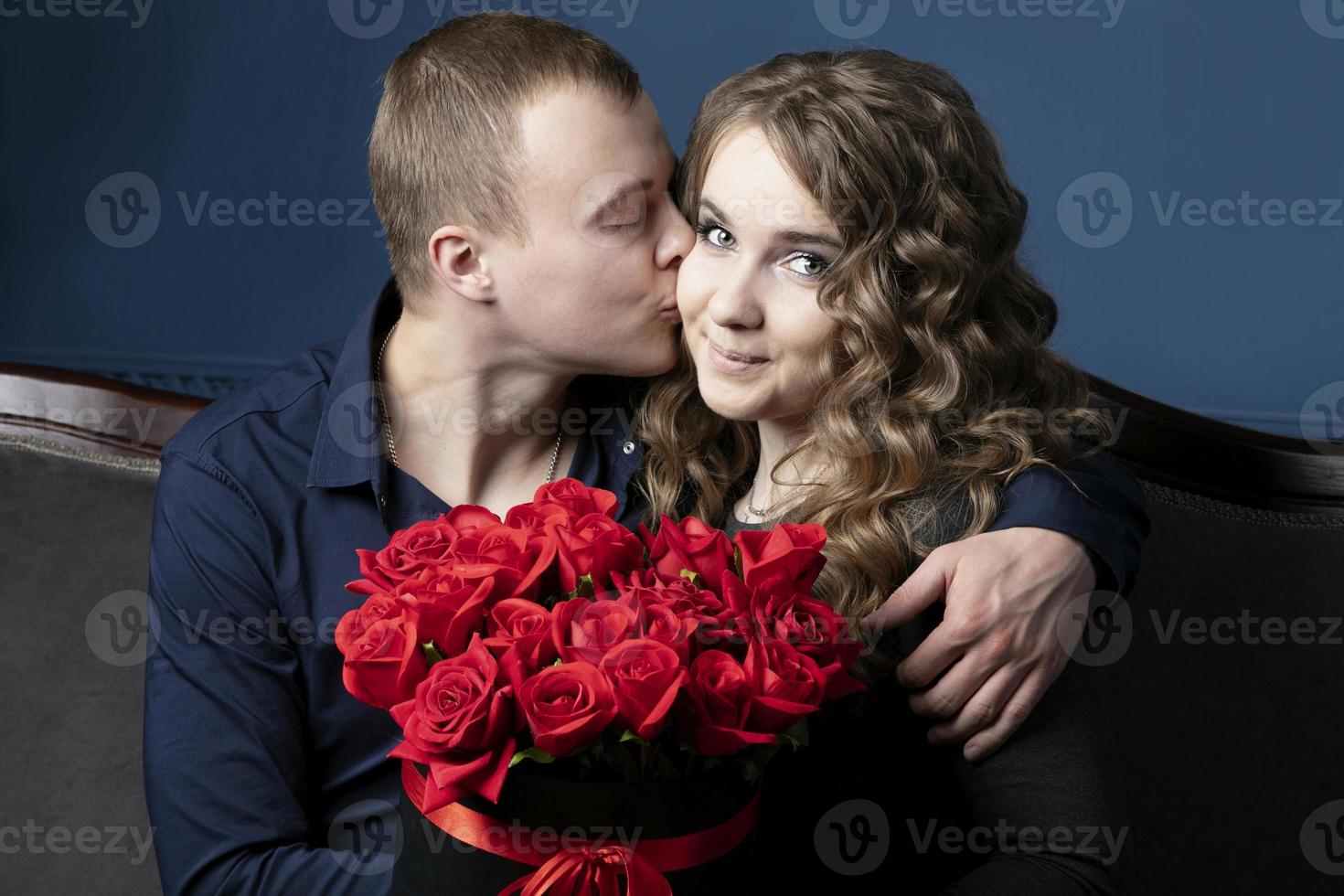 il tipo e il ragazza con un' mazzo di Rose. un' giovane coppia. amanti. un' uomo baci un' bellissimo donna. foto