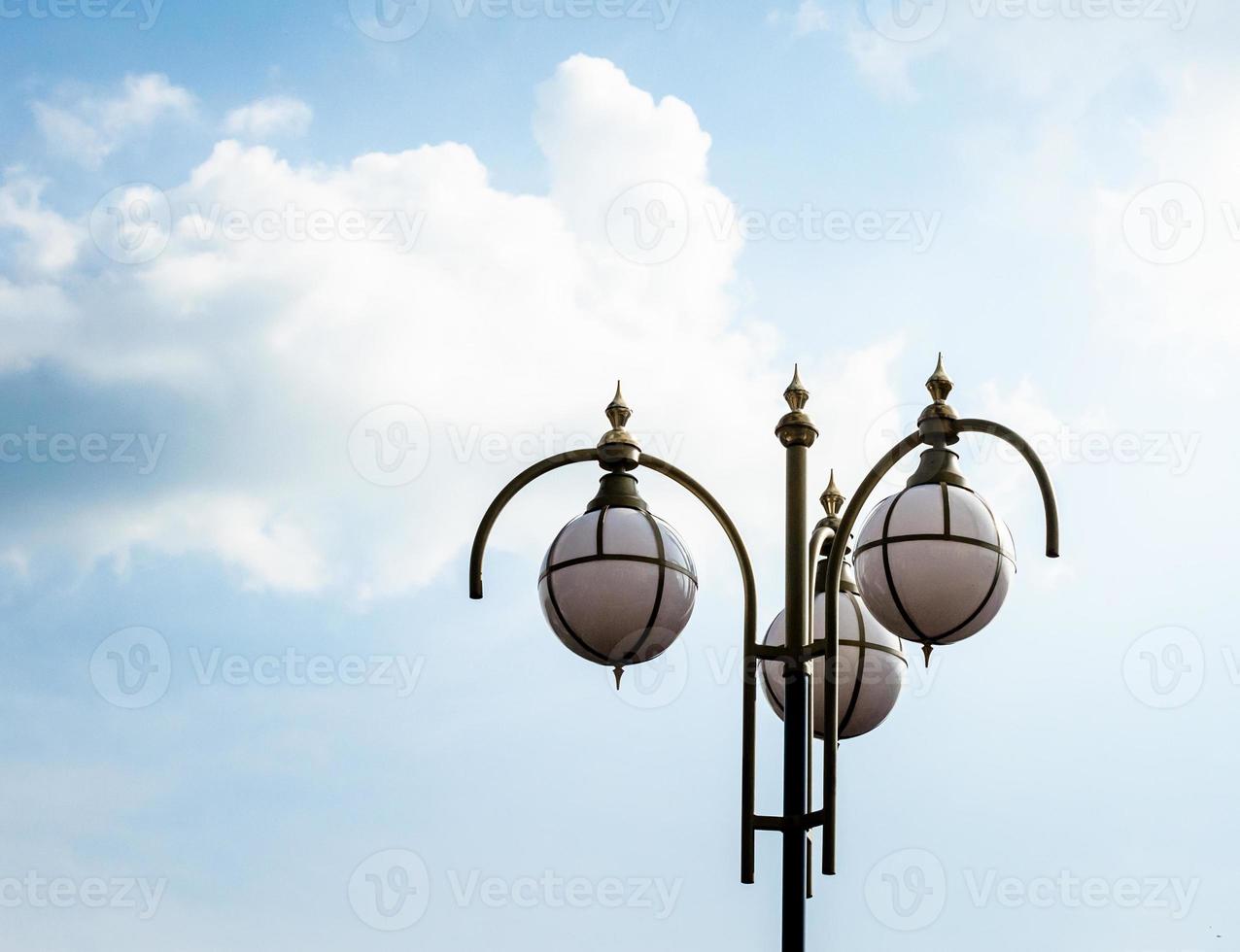 lampione contro un cielo azzurro e nuvole bianche foto