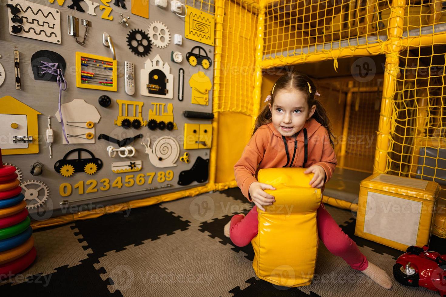 carino bambino in età prescolare ragazza giocando contro occupato tavola a bambini giocare centro. foto