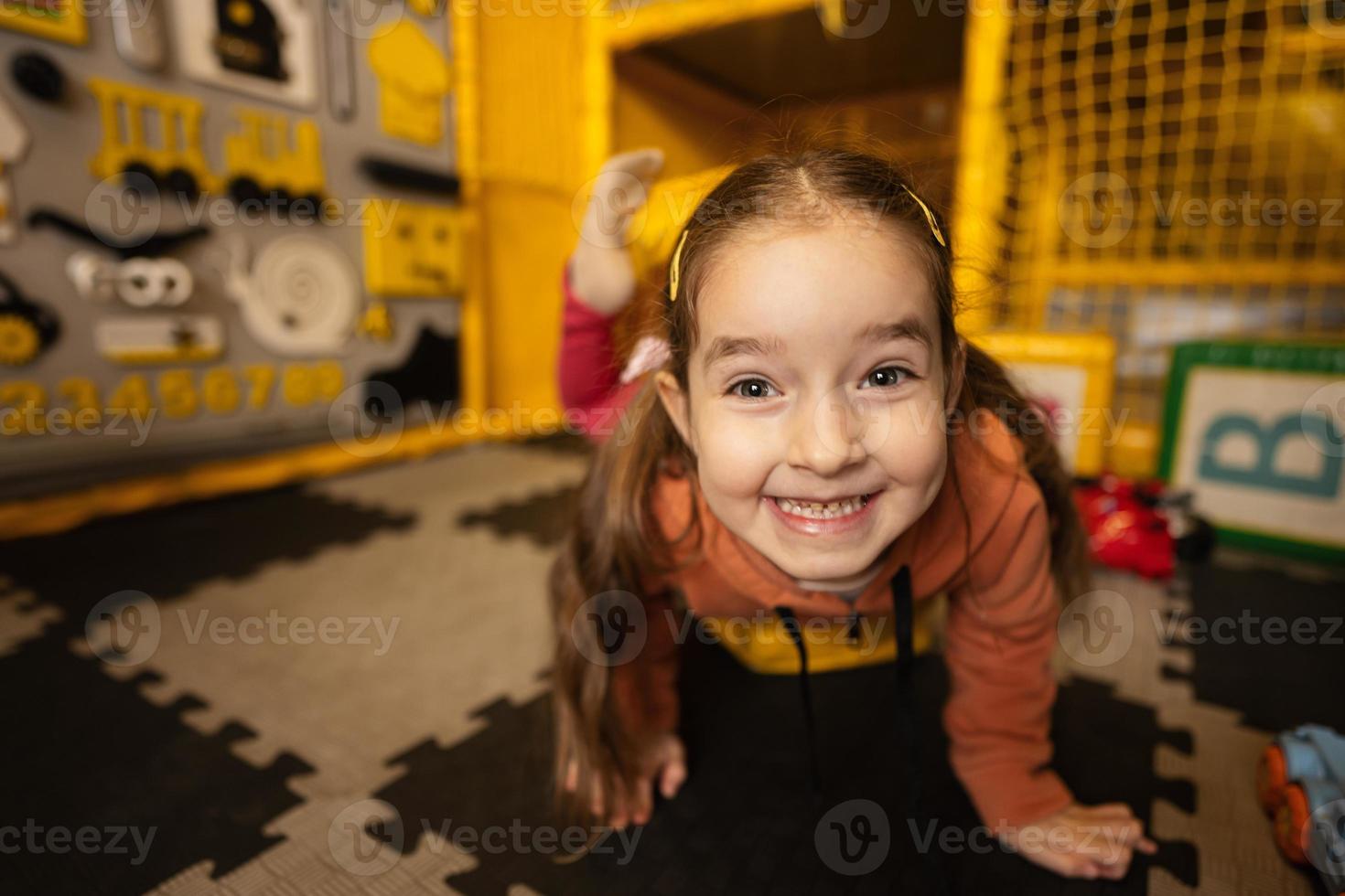 vicino su viso carino sorridente bambino in età prescolare ragazza giocando a bambini giocare centro. foto