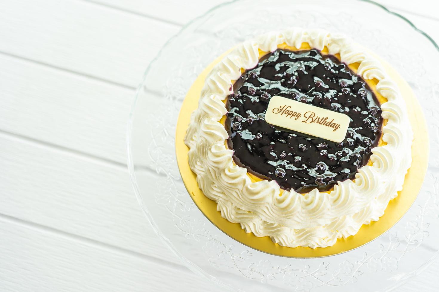 torta di formaggio ai mirtilli con segno di buon compleanno sulla parte superiore foto