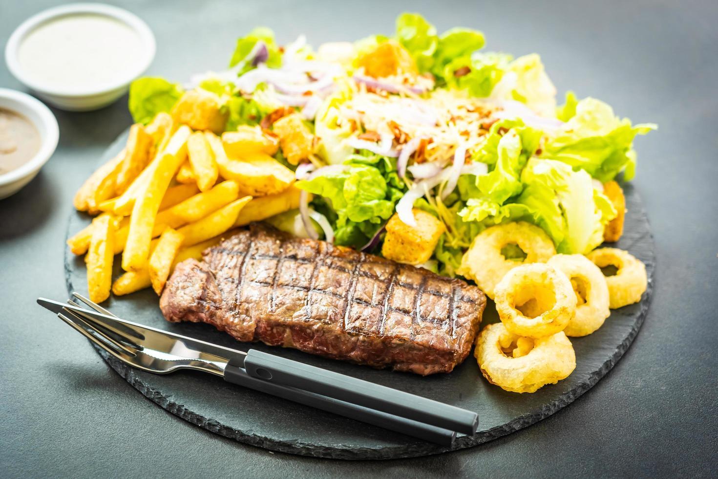 bistecca di carne di manzo alla griglia con patatine fritte anello di cipolla foto