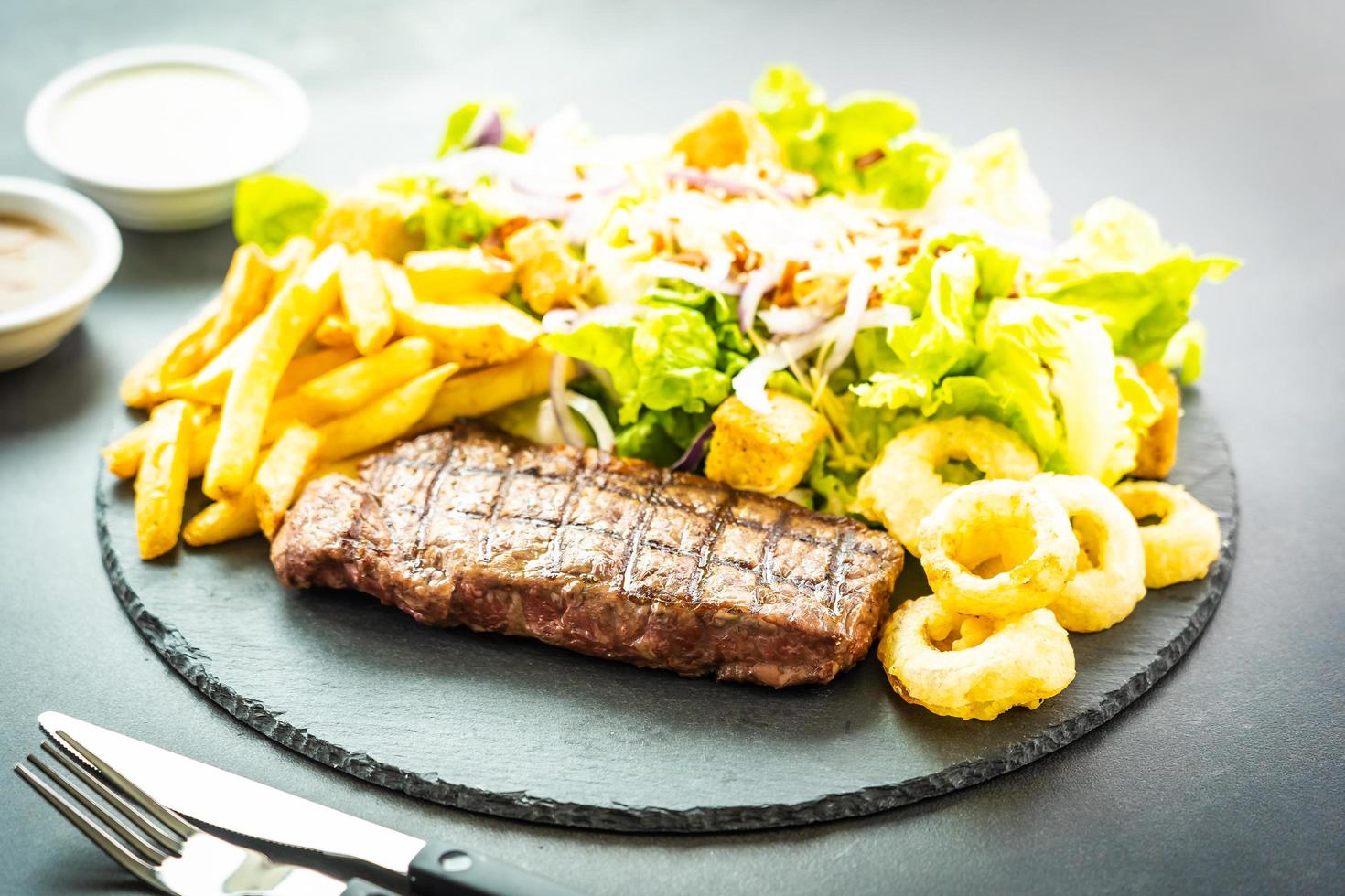 bistecca di carne di manzo alla griglia con patatine fritte anello di cipolla con salsa e verdura fresca foto