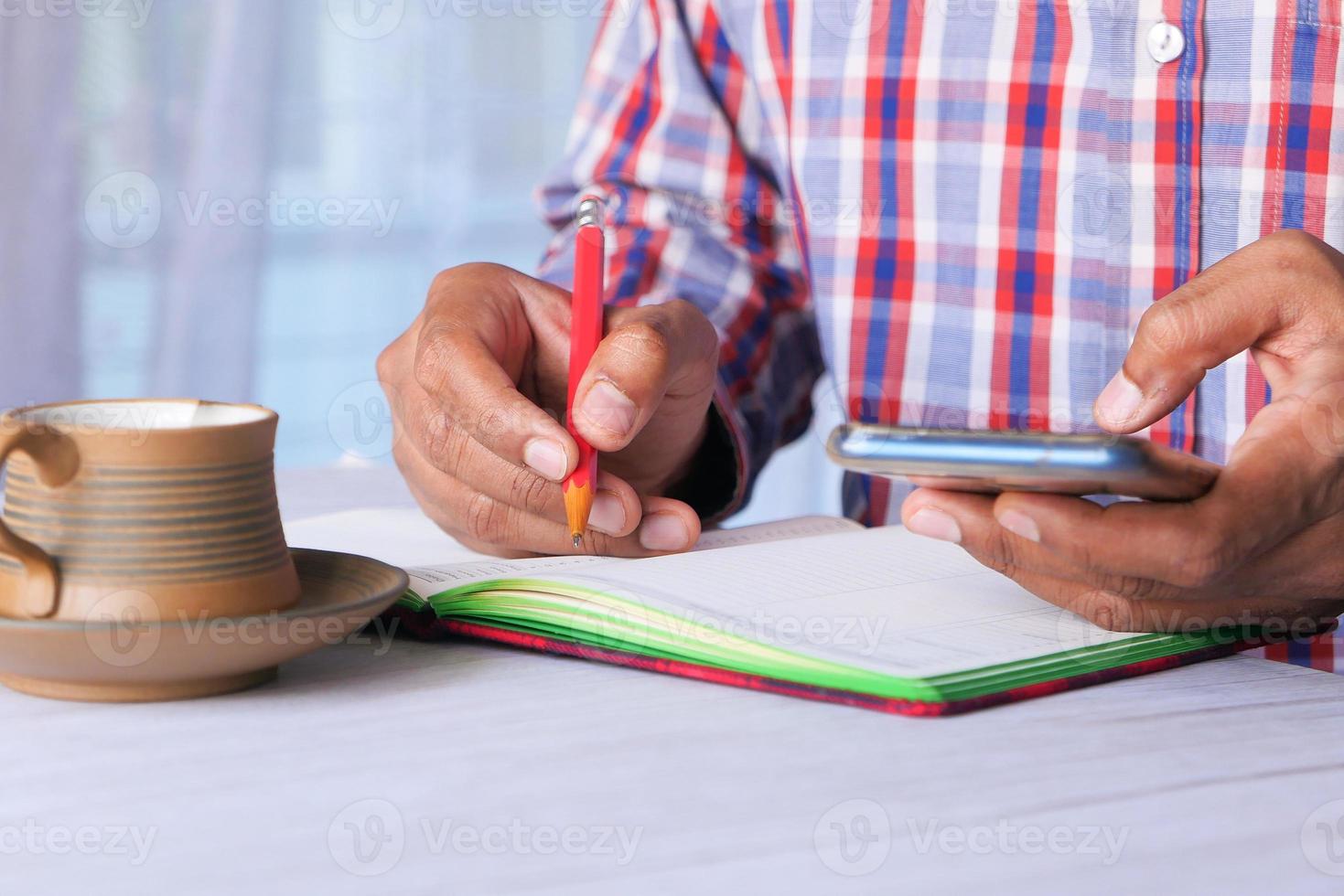 giovane uomo scrivendo e utilizzando smart phone sulla scrivania in ufficio foto