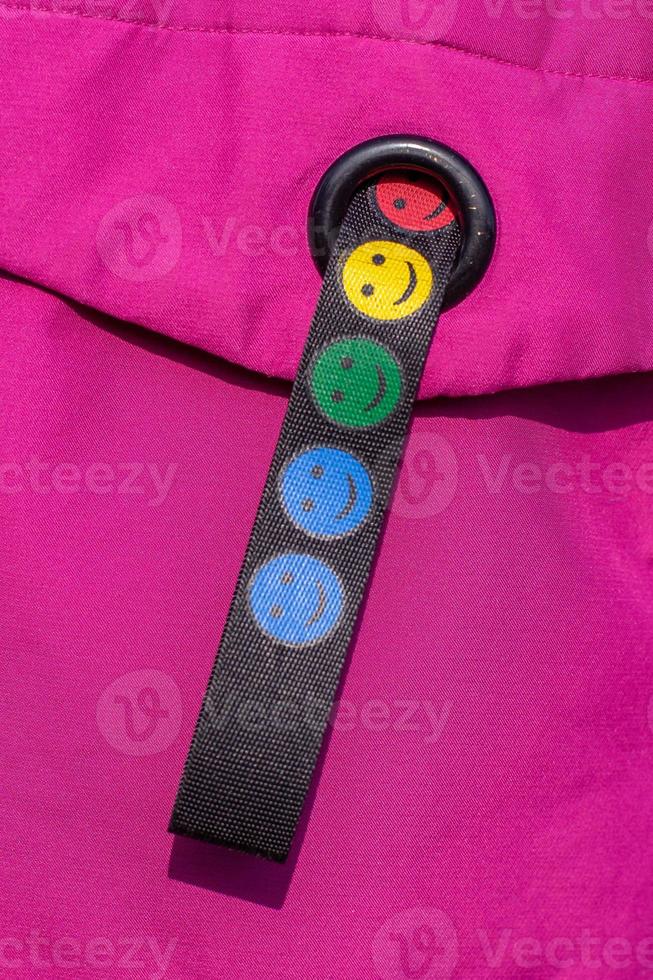 multicolore sorridente emoticon su un' tessuto cinghia. nero cinghia su un' rosso sfondo. verticale. foto