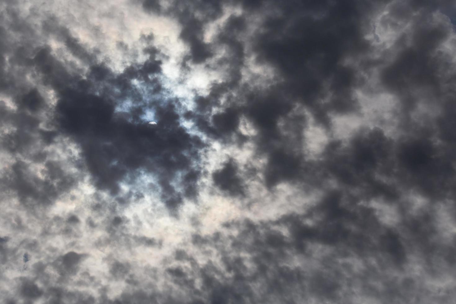 Visualizza su sole nascosto dietro a buio nuvole foto