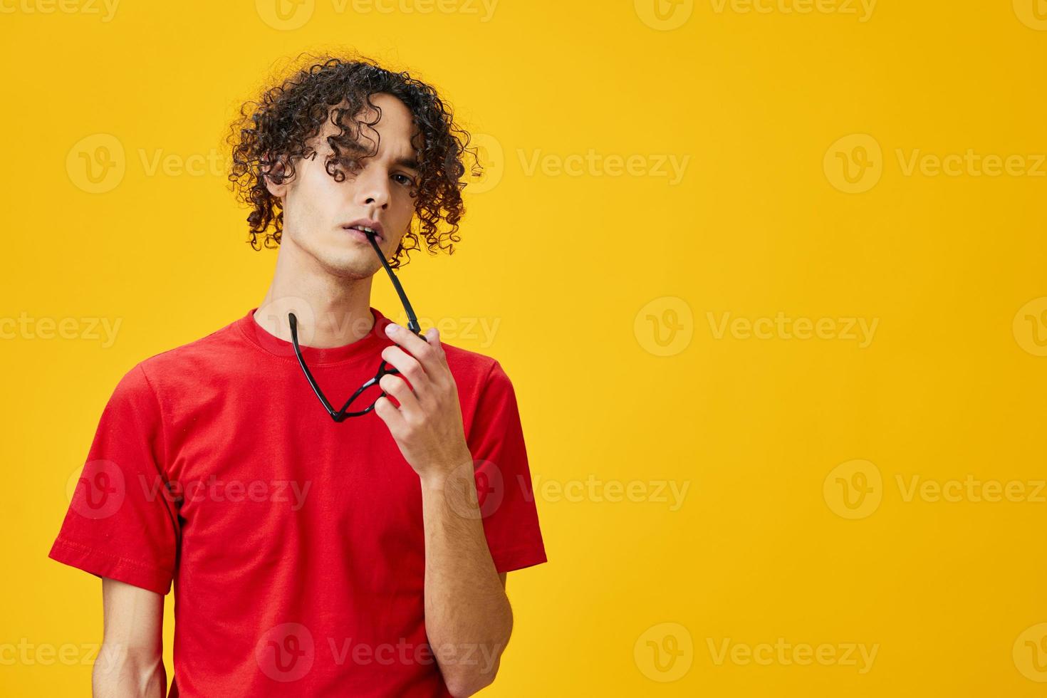 incredulo miope giovane alunno uomo nel rosso maglietta hold divertente occhiali su denti in posa isolato su giallo studio sfondo. il migliore offrire con gratuito posto per pubblicità. formazione scolastica Università concetto foto