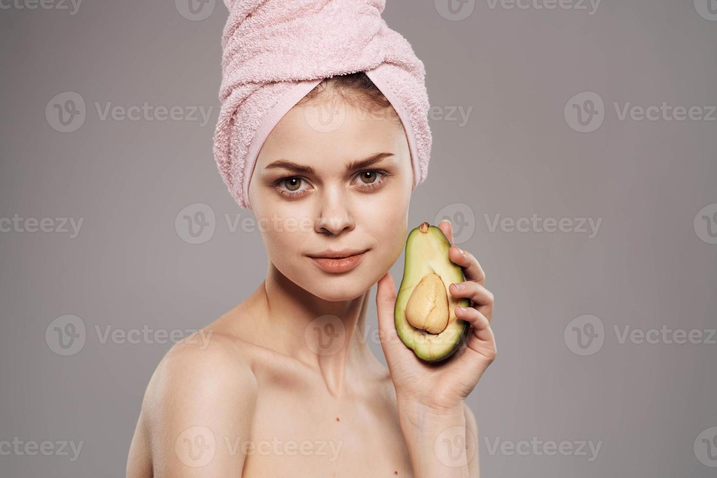 allegro donna con un' asciugamano su sua testa ritagliata Visualizza di un avocado nel sua mano foto