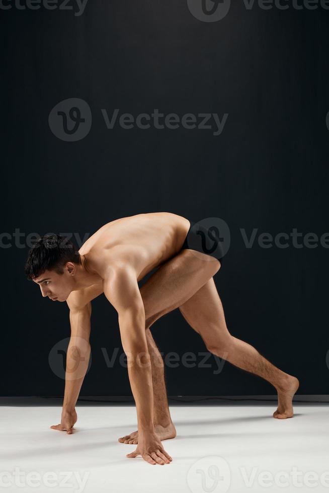 maschio bodybuilder nel nero pantaloncini su un' buio sfondo foto