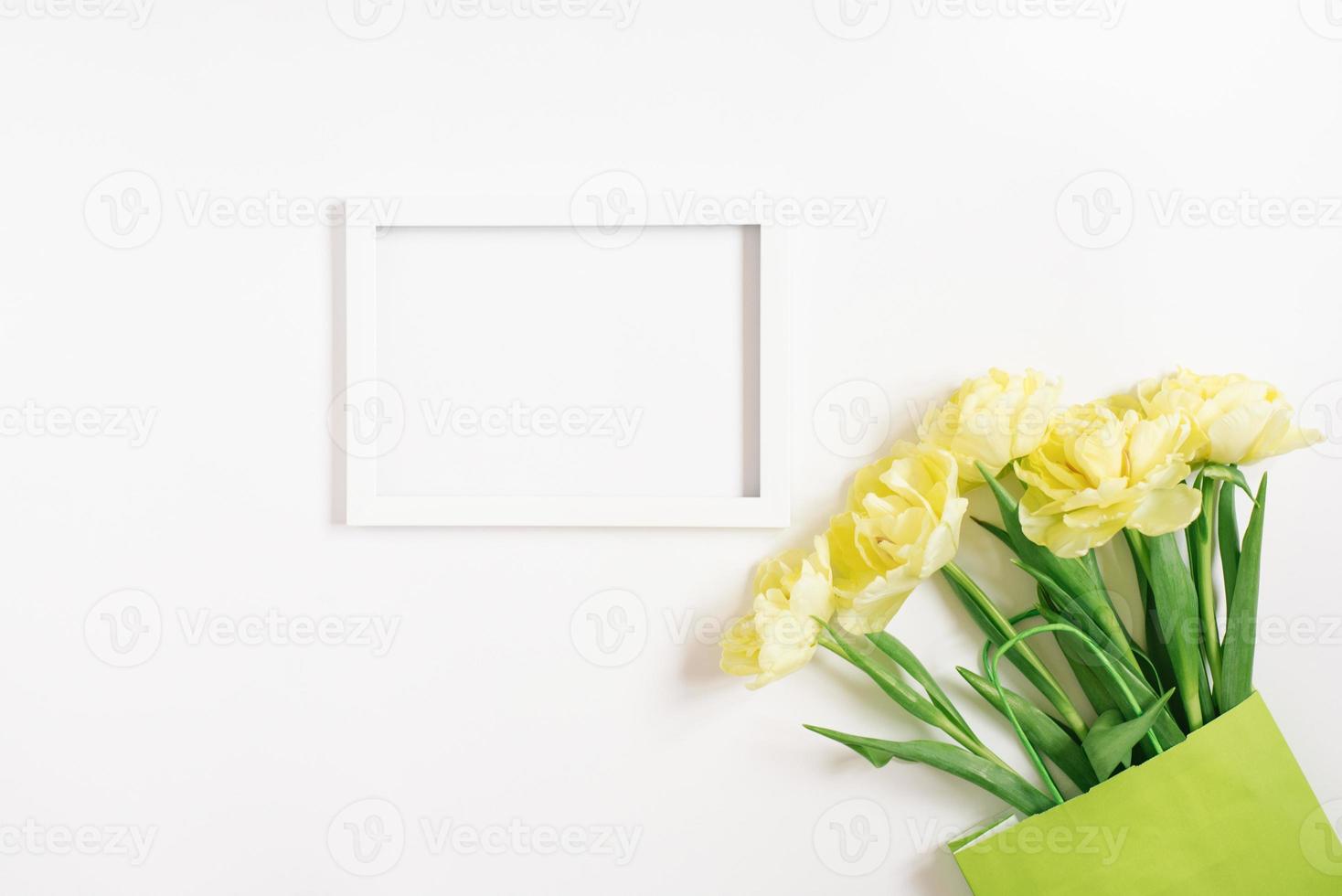 un' verde carta Borsa con primavera fiori di giallo tulipani e un' bianca vuoto testo telaio su un' bianca sfondo. piatto disposizione, superiore Visualizza, copia spazio, modello foto