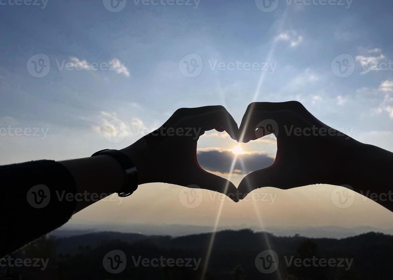 luce del sole brilla attraverso a forma di cuore mani. sera cielo sfondo. morbido e selettivo messa a fuoco. foto