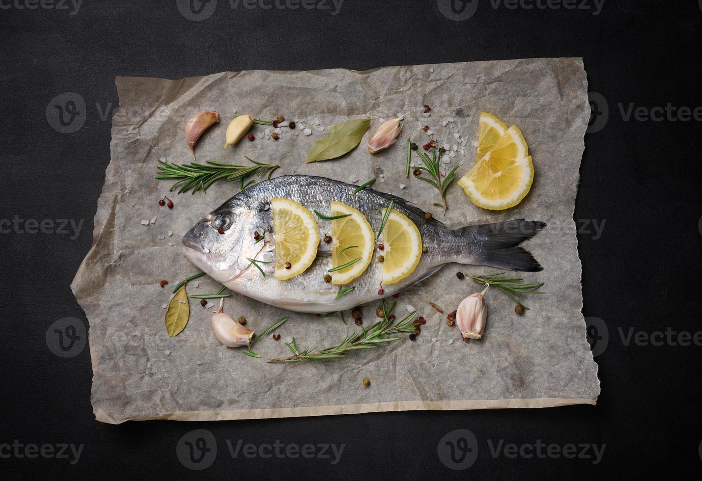 crudo totale dorado pesce su Marrone pergamena carta e spezie per cucinando, superiore Visualizza su nero tavolo foto