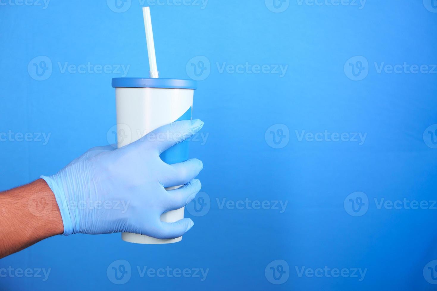 mano in guanti protettivi che tengono tazza di caffè eco riutilizzabile foto