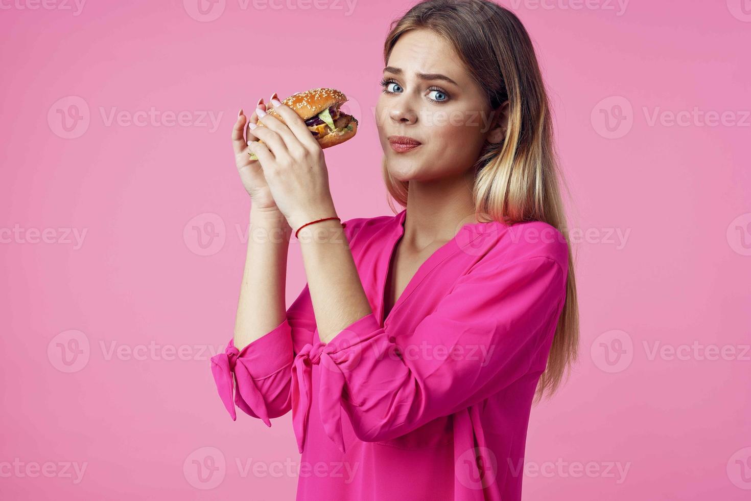 allegro bionda nel un' rosa camicia Hamburger veloce cibo merenda foto