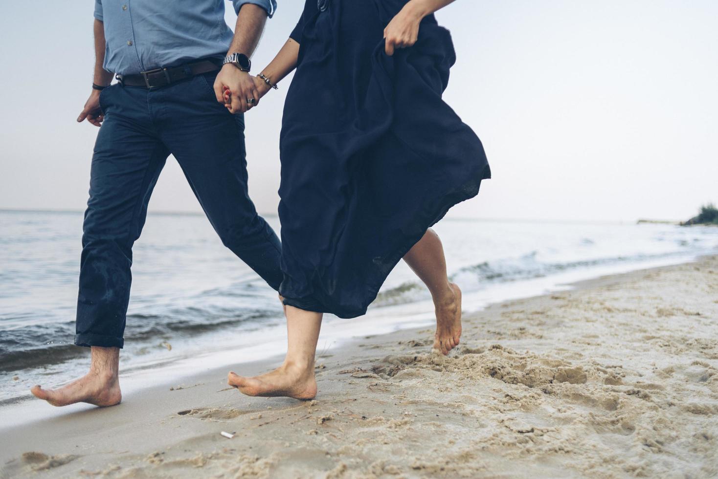 coppia che corre lungo una spiaggia foto