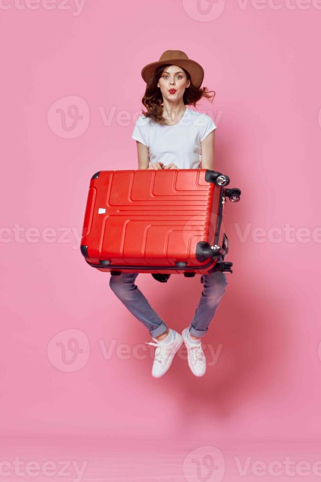allegro donna con valigia bagaglio viaggio divertimento rosa sfondo foto