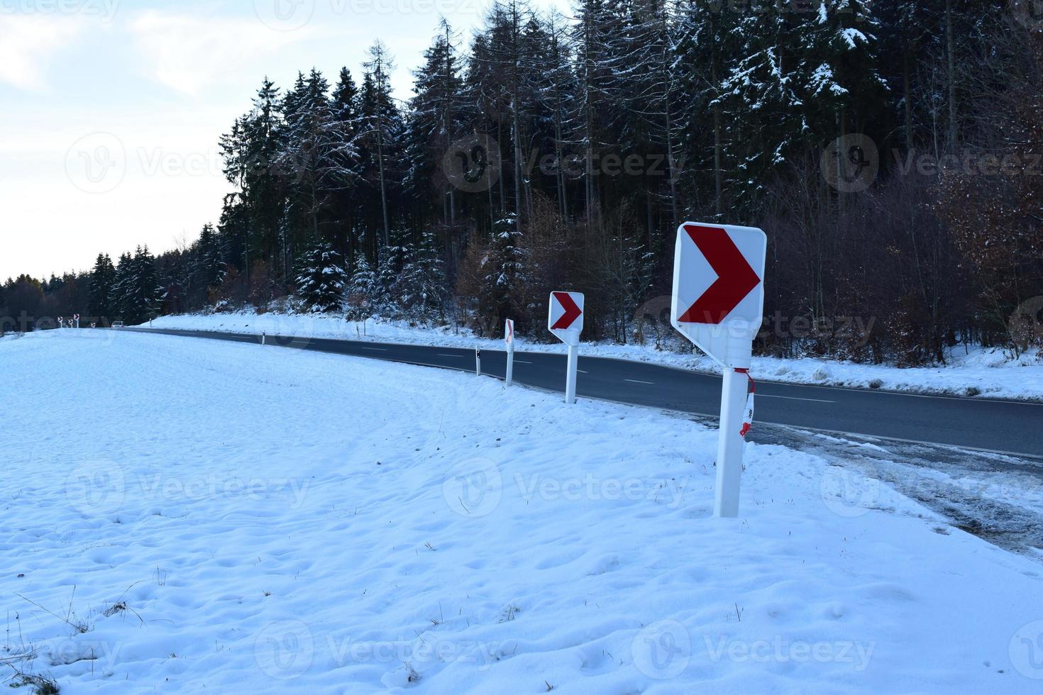 strada curva con neve e warning segni foto