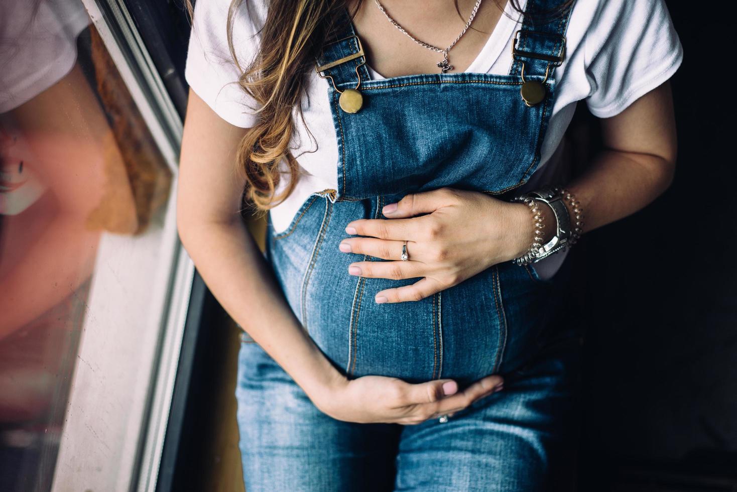 donna incinta seduta vicino al davanzale della finestra foto