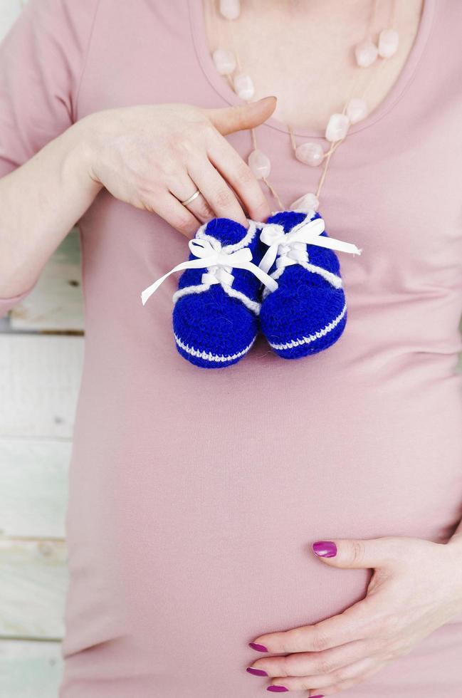 donna incinta con scarpe per bambini foto