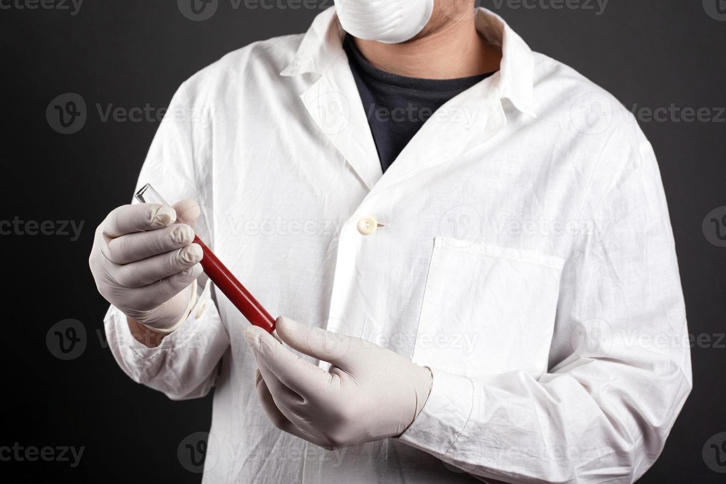 un medico in uniforme medica tiene una provetta con il sangue nelle sue mani foto