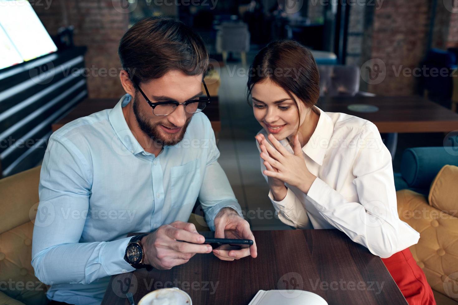 uomo e donna seduta a il tavolo vicino il Telefono comunicazione di opera colleghi foto