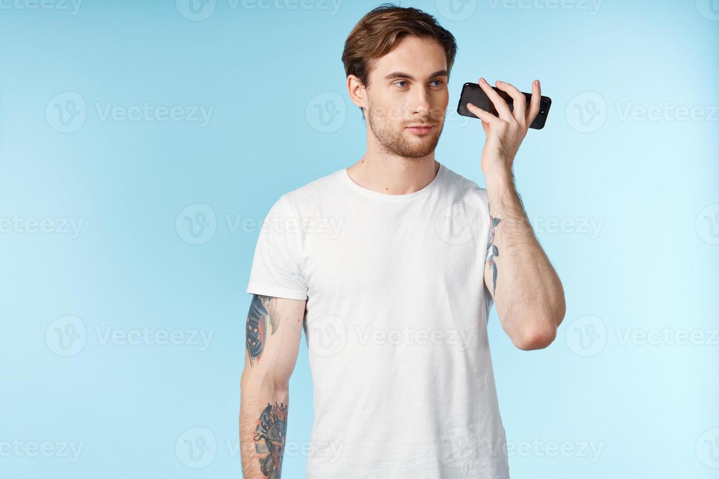 uomo con tatuaggi su il suo braccia bianca maglietta ritagliata Visualizza blu sfondo foto