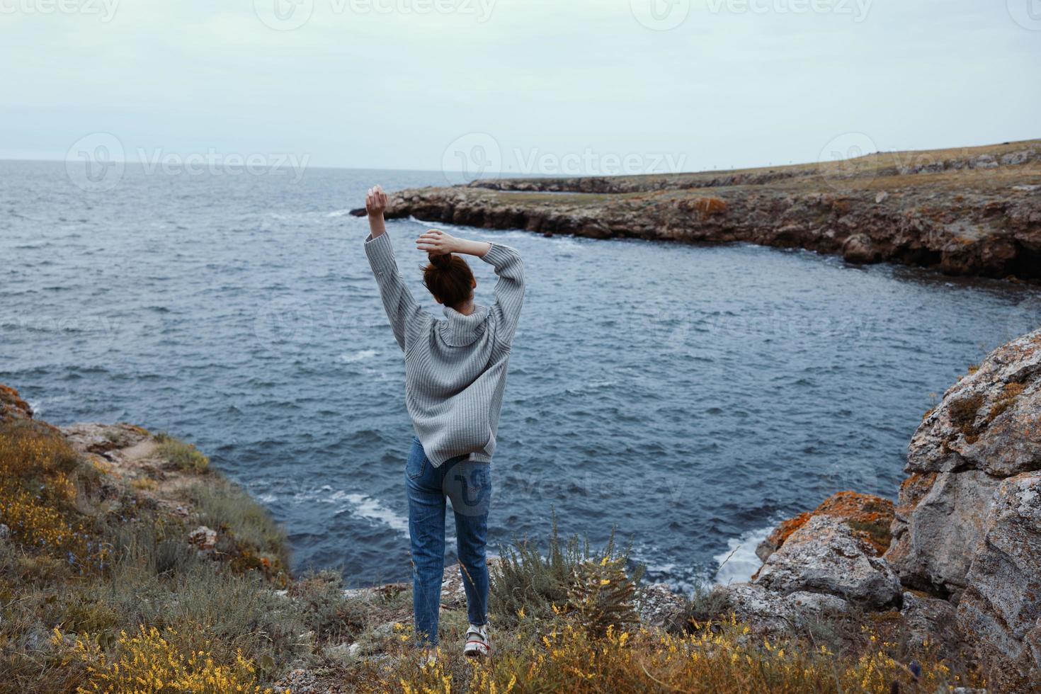 bella donna nel un' grigio maglione sta su un' roccioso riva natura rilassamento concetto foto