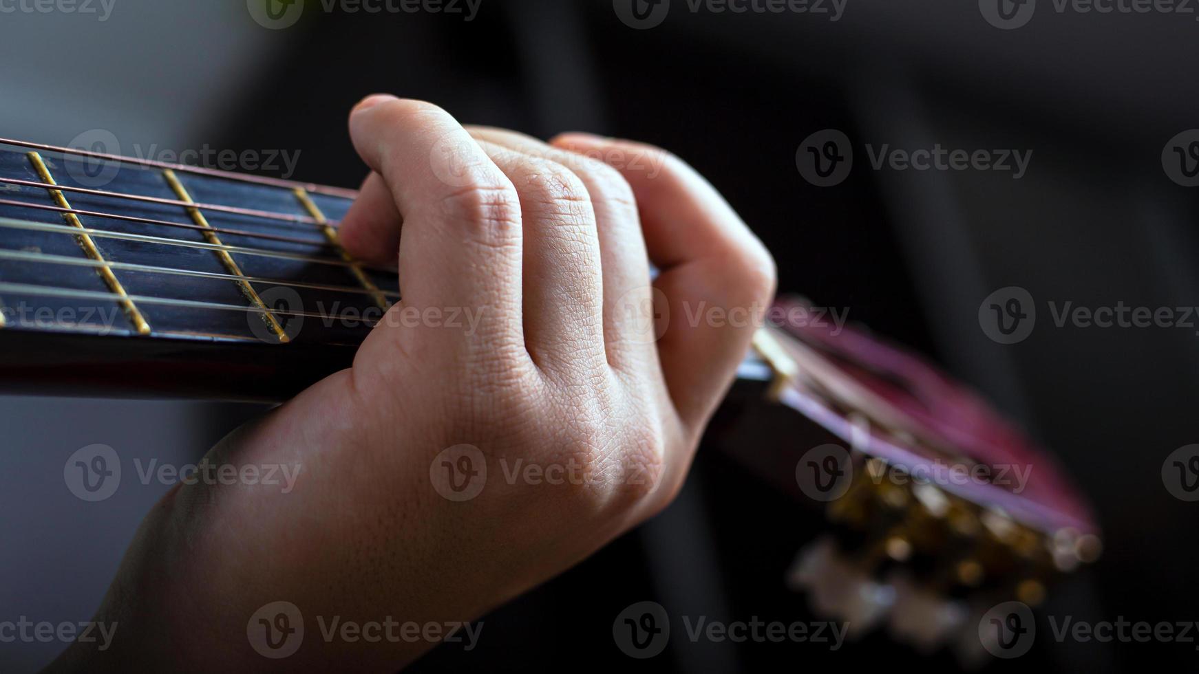 mano maschile tiene un accordo su una chitarra acustica a sei corde foto