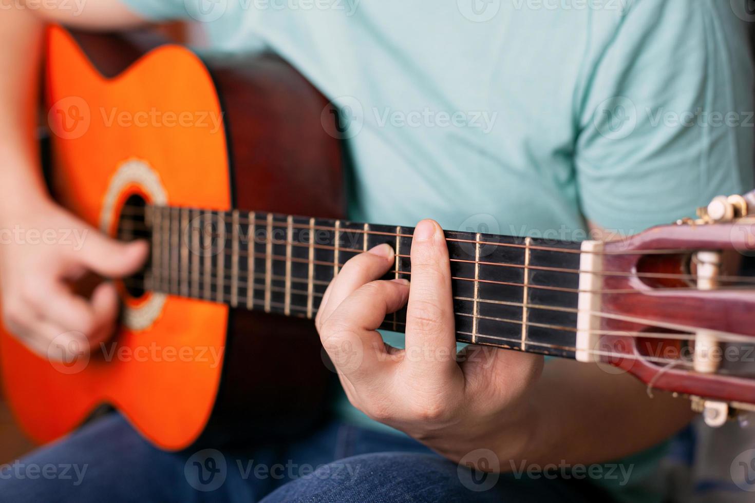 ragazzo suona la chitarra acustica, il dito tiene un accordo bar foto