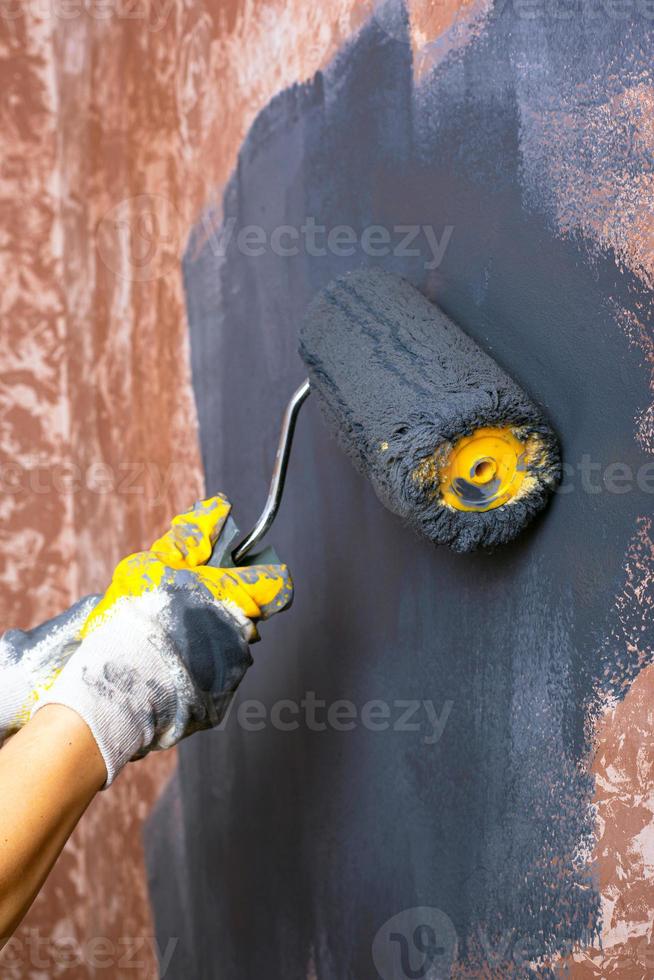 dipingere le pareti con un rullo di colore grigio foto