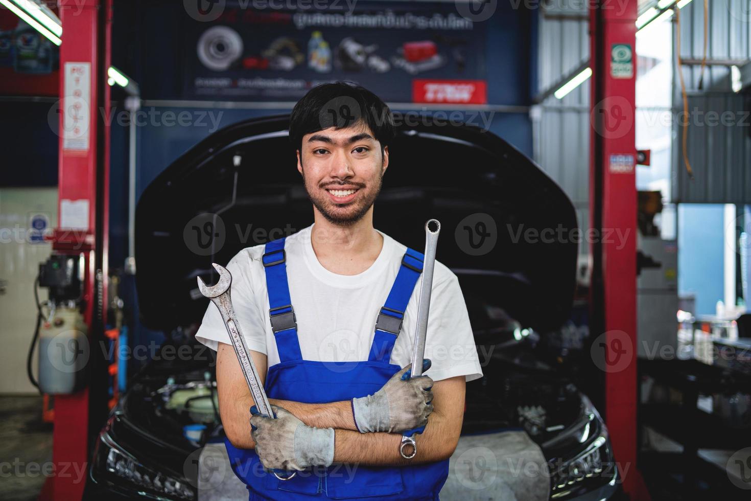 ritratto di sorridente asiatico maschio riparatore Tenere a gambe incrociate chiave inglese a box auto professionale riparazione e Manutenzione. auto ispezione servizio foto