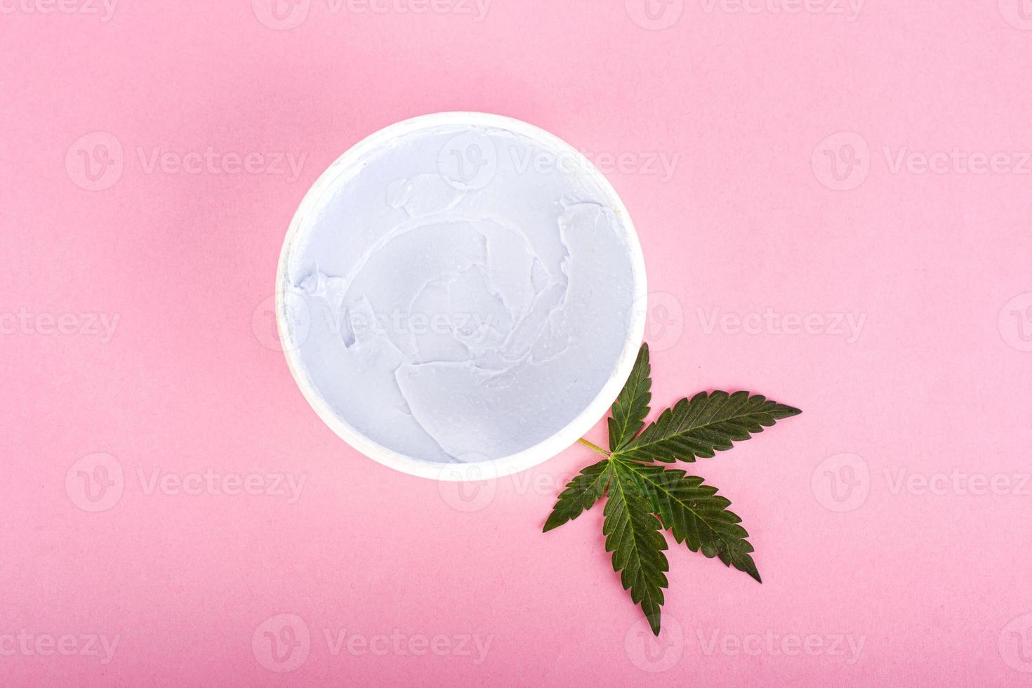 cosmetici alla cannabis, crema di marijuana naturale e foglia verde su sfondo rosa foto