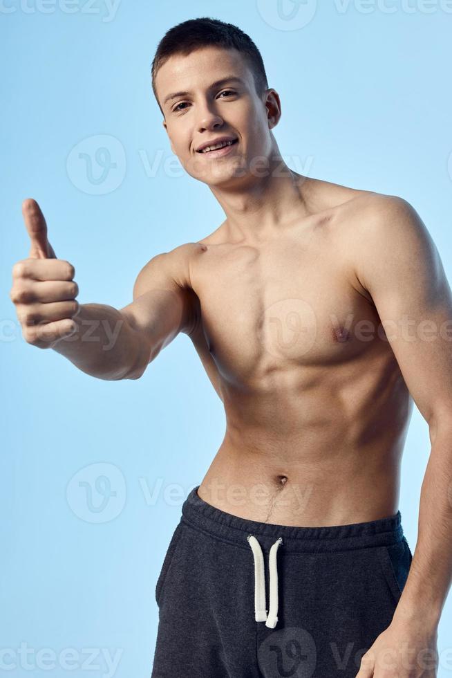 nudo atleta mostrando pollice e pantaloncini blu sfondo modello foto