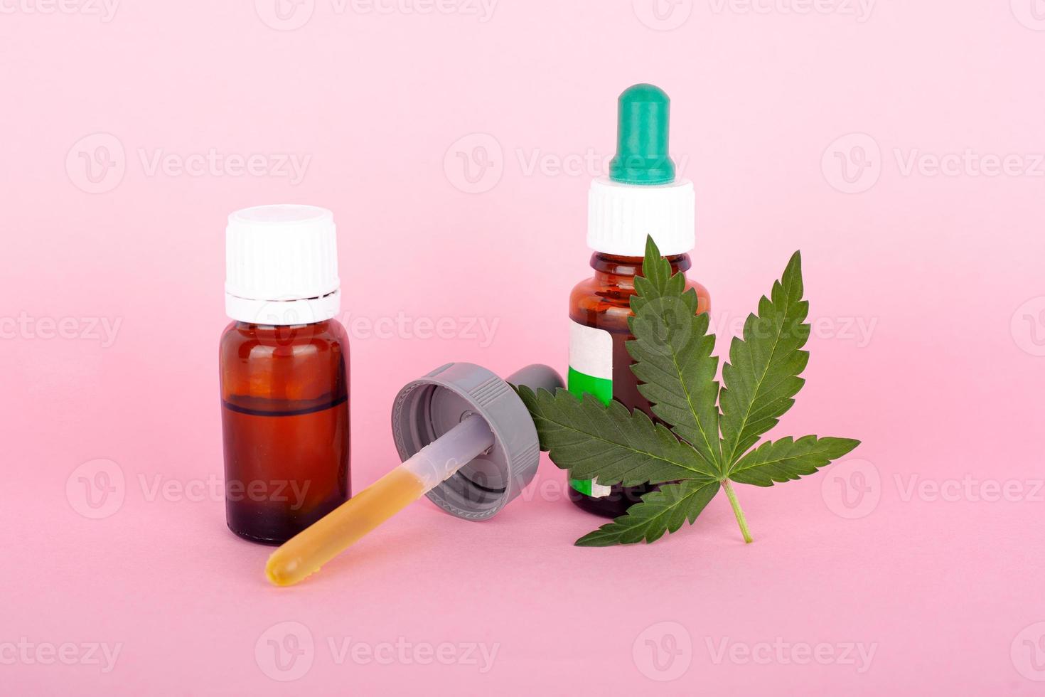 concetto di marijuana medica con foglia di cannabis e pipetta su sfondo rosa foto