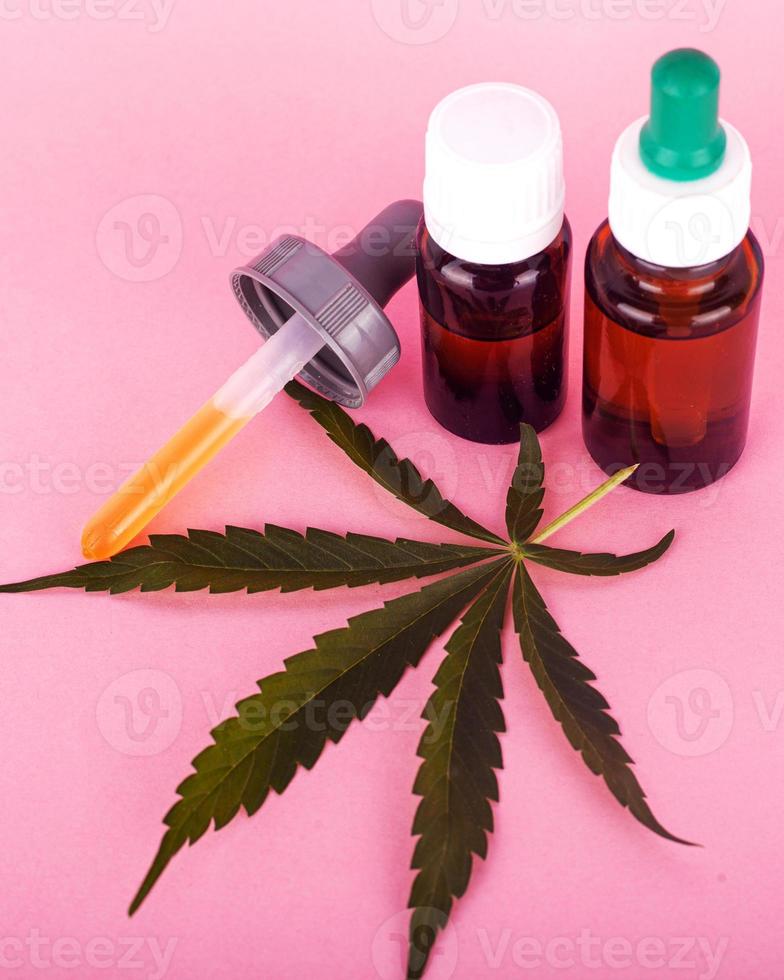 olio di canapa per uso medico, bottiglie con estratto di cannabis medica su sfondo rosa foto