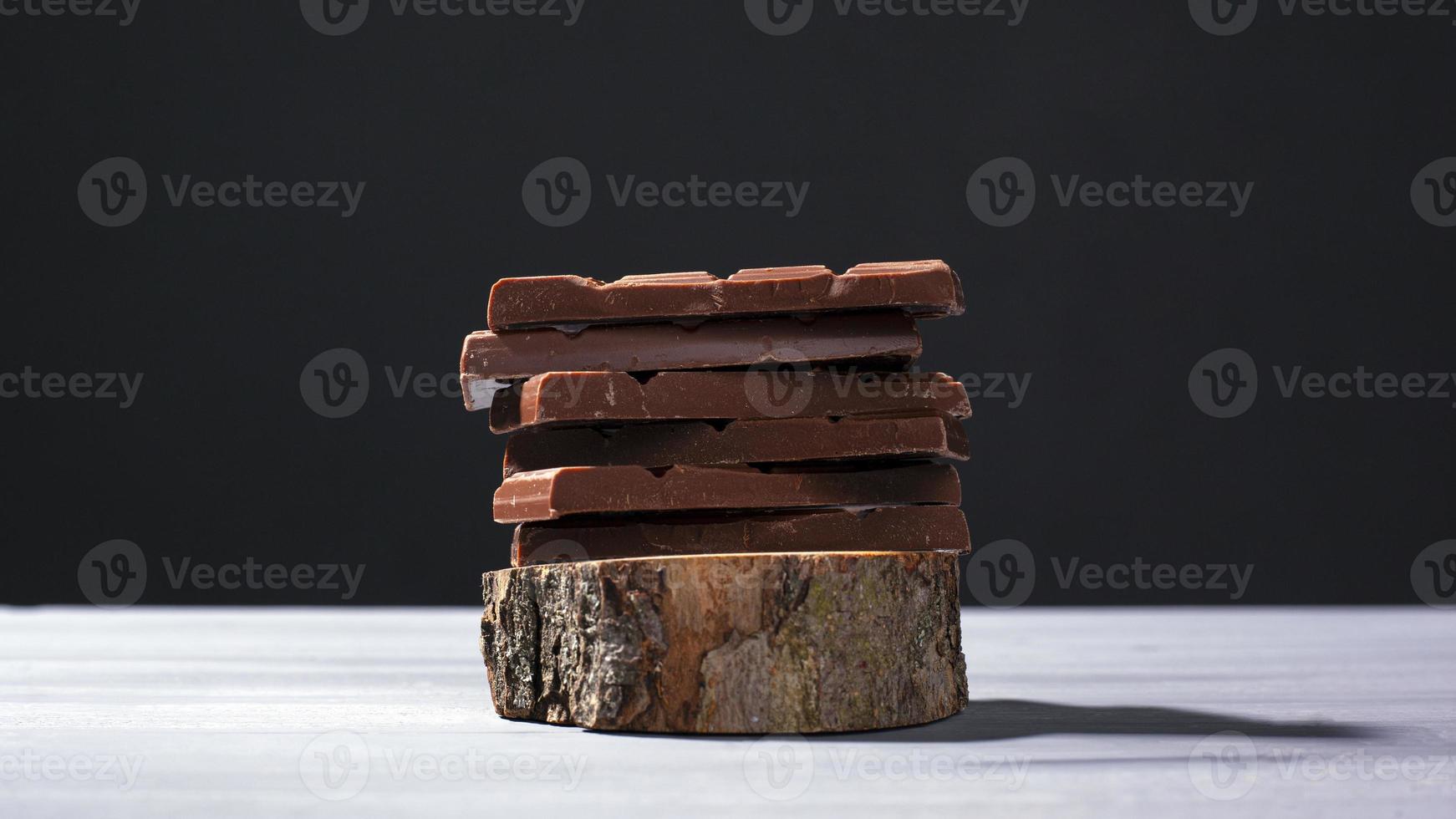 pezzi di cioccolato al latte su un supporto di legno su uno sfondo grigio foto