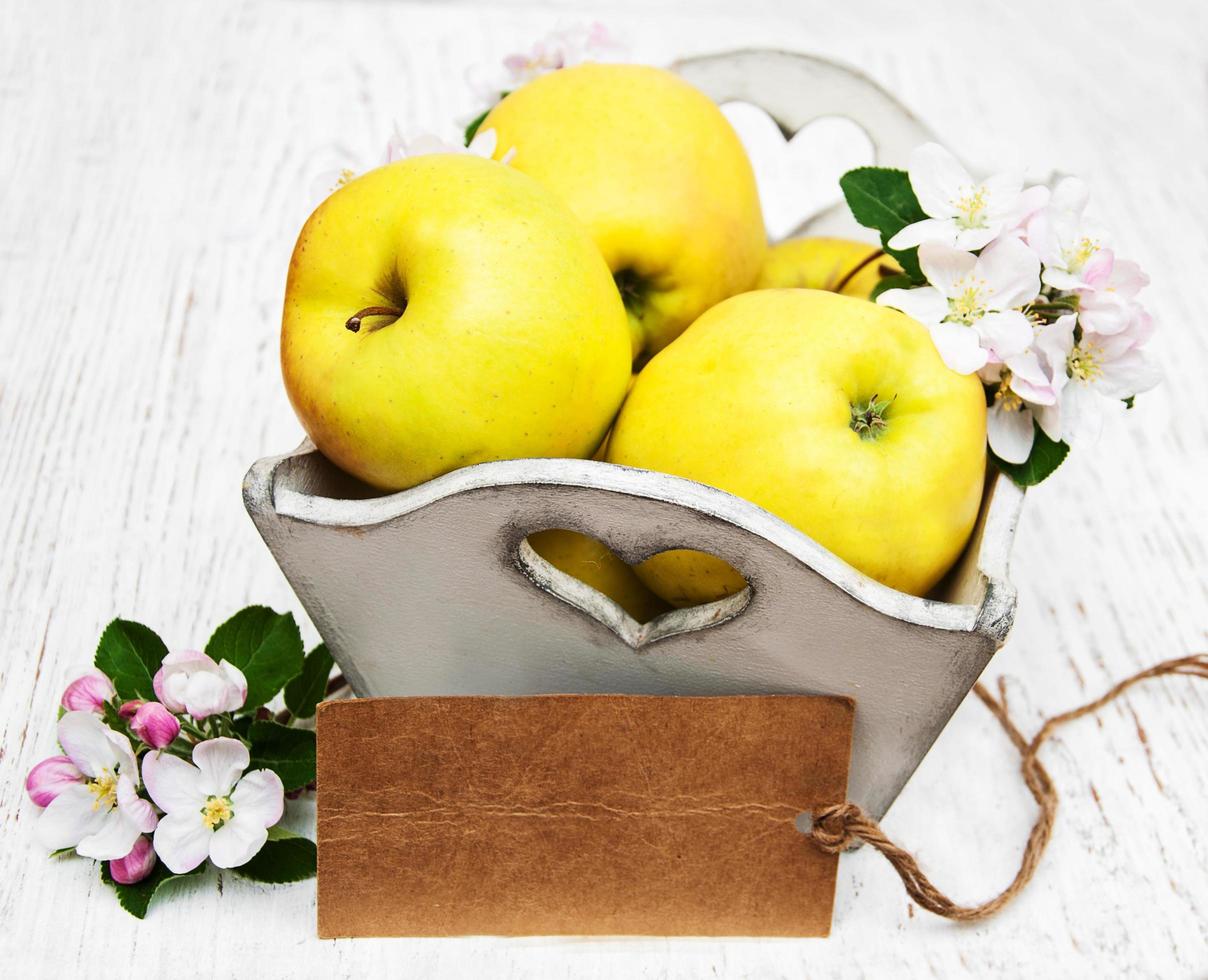 scatola con mele e fiori di melo e un tag vuoto su un tavolo di legno foto
