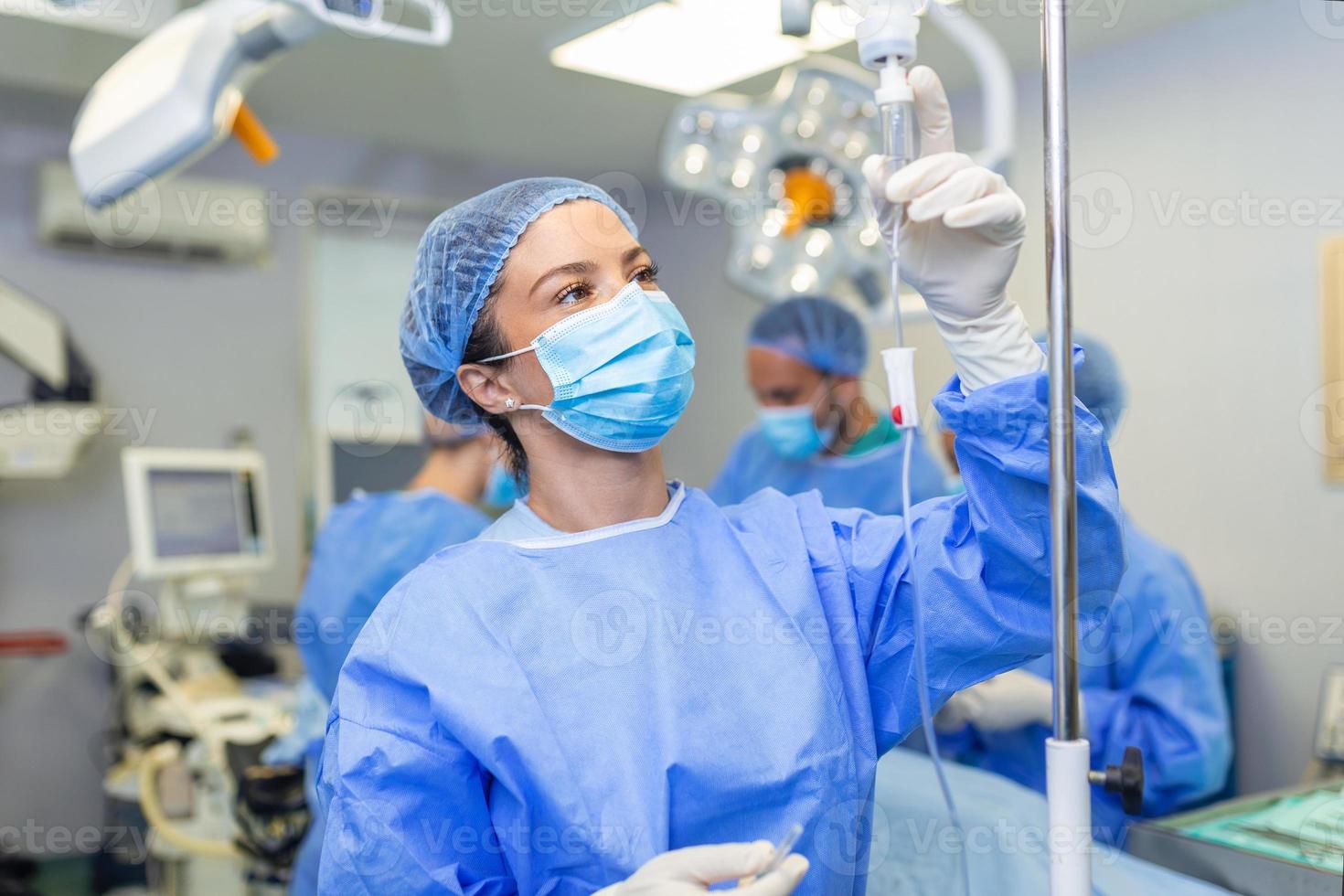 femmina medico nel il operativo camera mettendo farmaci attraverso un iv - chirurgia concetti foto
