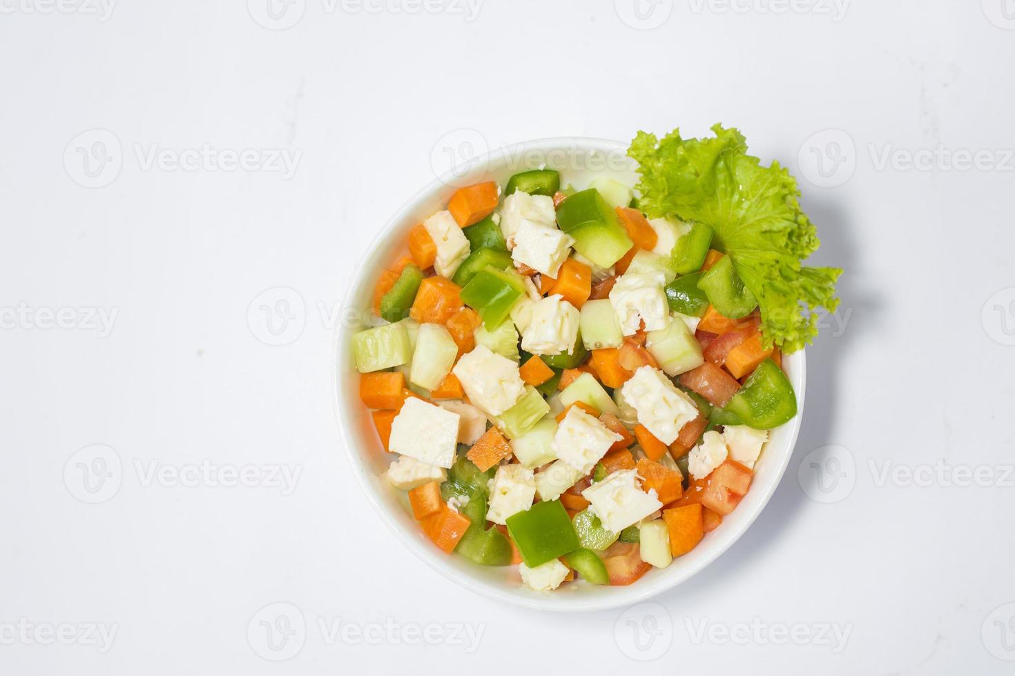 fresco verde verdura insalata nel un' piatto. salutare peperone, carota, formaggio, pomodoro e lattuga pasto su bianca sfondo foto