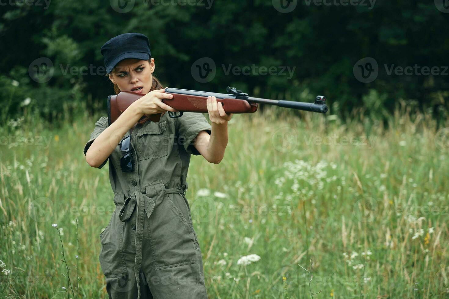 donna Tenere un' arma mirando a caccia fresco aria verde tuta da lavoro foto