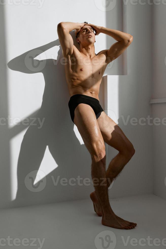 uomo con un' muscolare corpo nel nero mutandine vicino il finestra foto