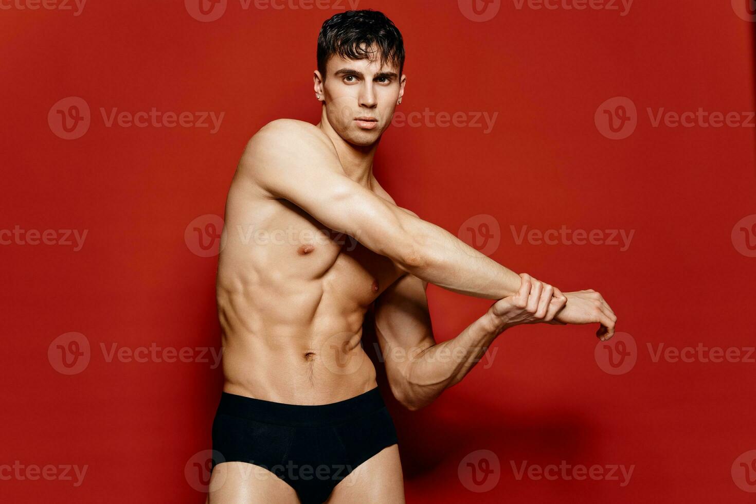 giovane tipo atleta con un gonfiato torso e braccio muscoli posa su un' rosso sfondo foto
