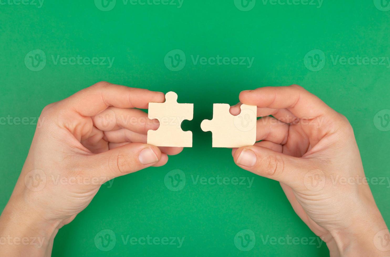 pezzi del puzzle nelle mani su uno sfondo verde foto