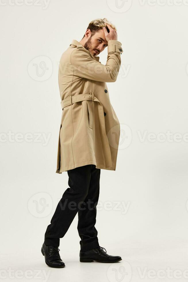 bello uomo nel beige cappotto attraente Guarda studio moderno stile leggero sfondo foto