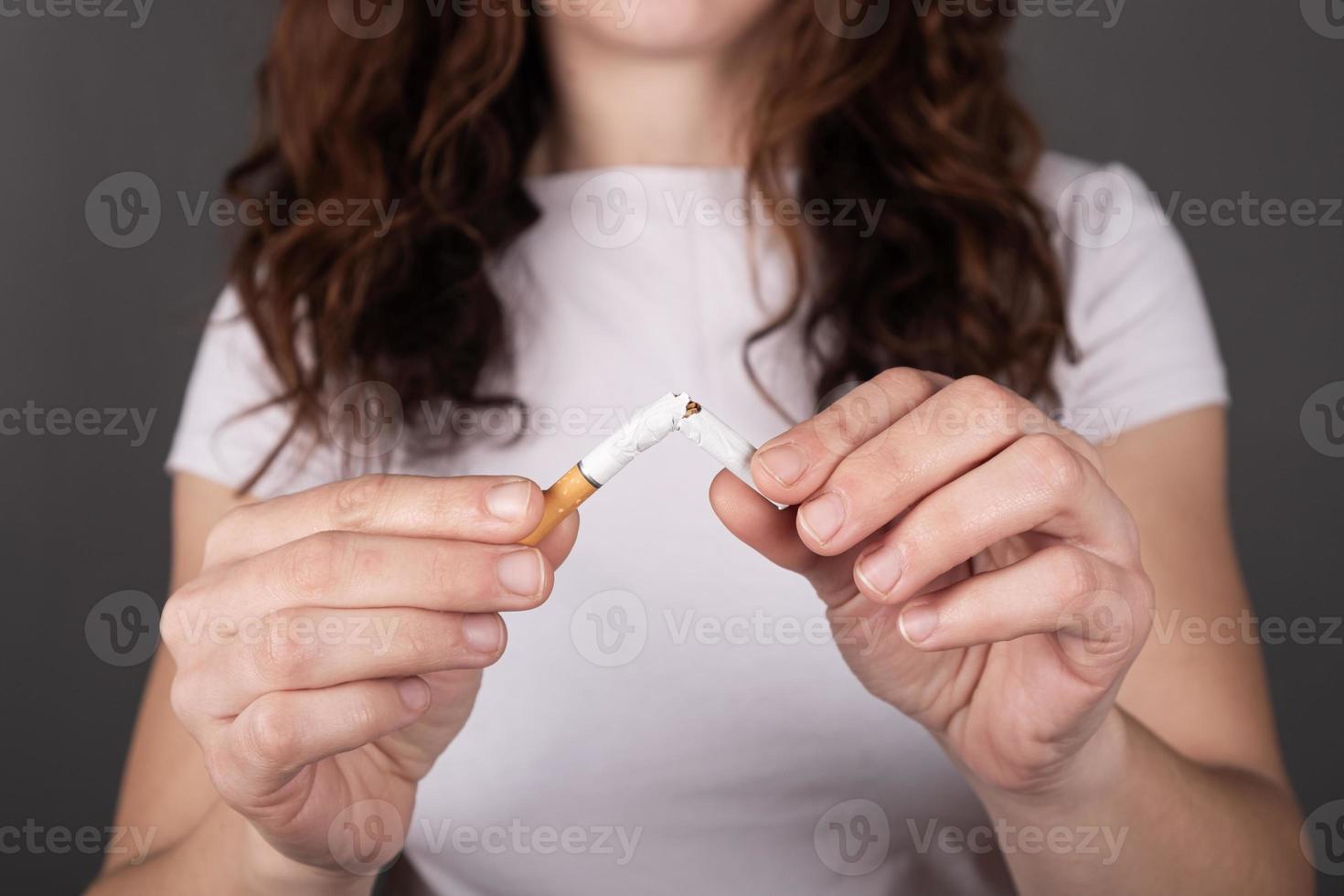 sigaretta rotta in mani femminili, smettere di fumare segno foto