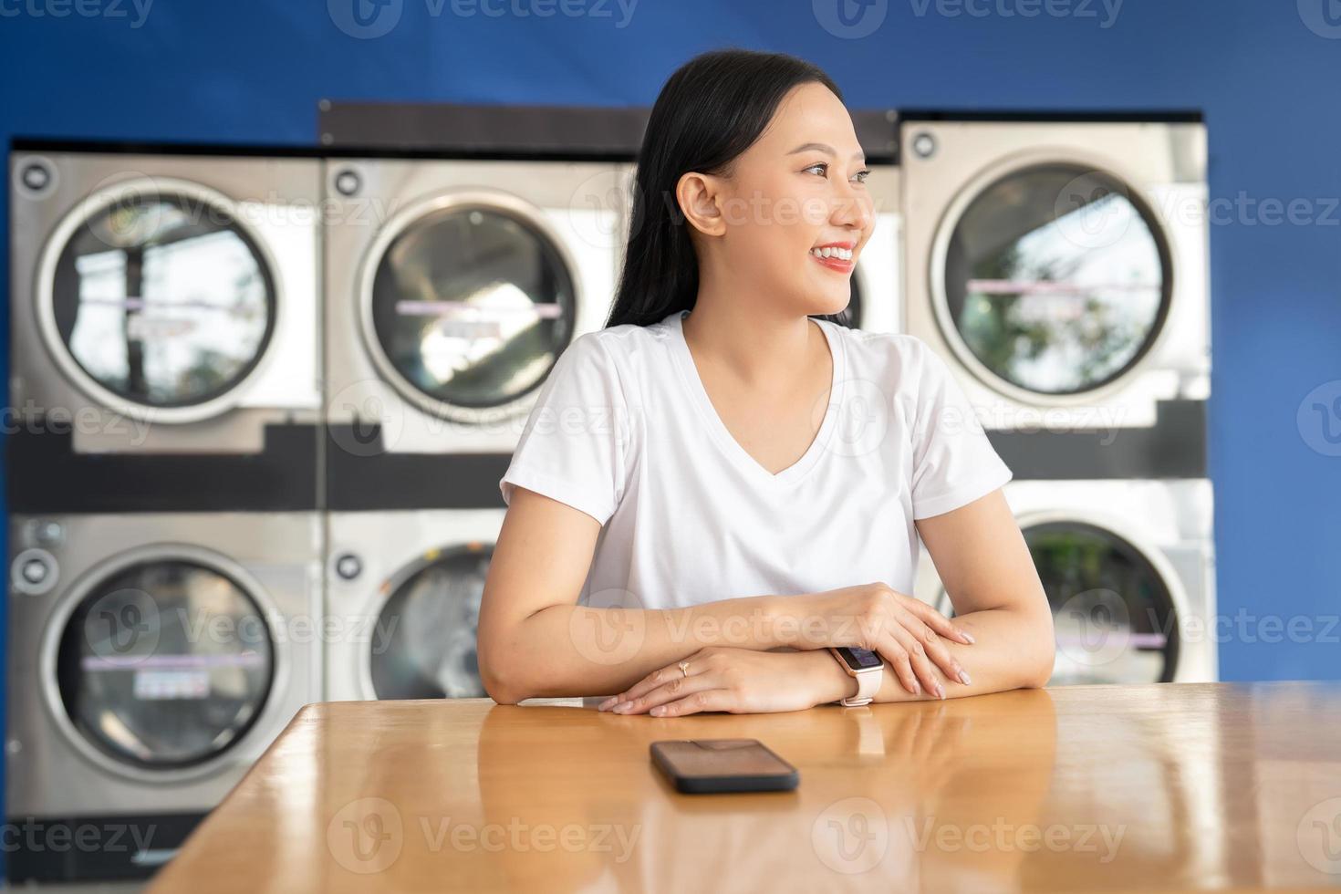 contento asiatico donna fare lavanderia lei era in attesa per lavanderia nel il Lavorando lavaggio macchina nel il nuovo normale stile di vita condominio città. foto