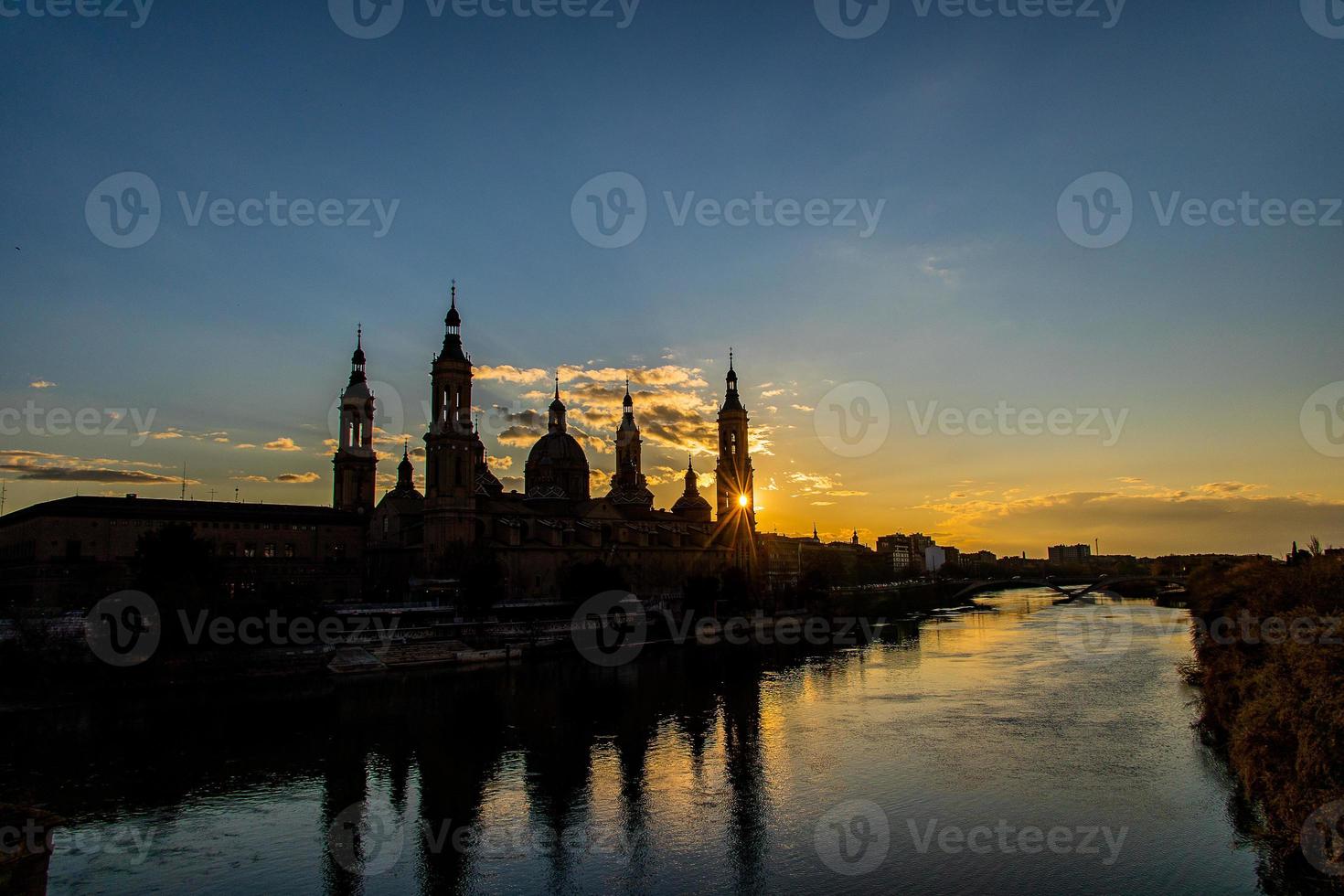 urbano tramonto al di sopra di il Pilar Cattedrale nel saragozza, Spagna e il ebro fiume foto