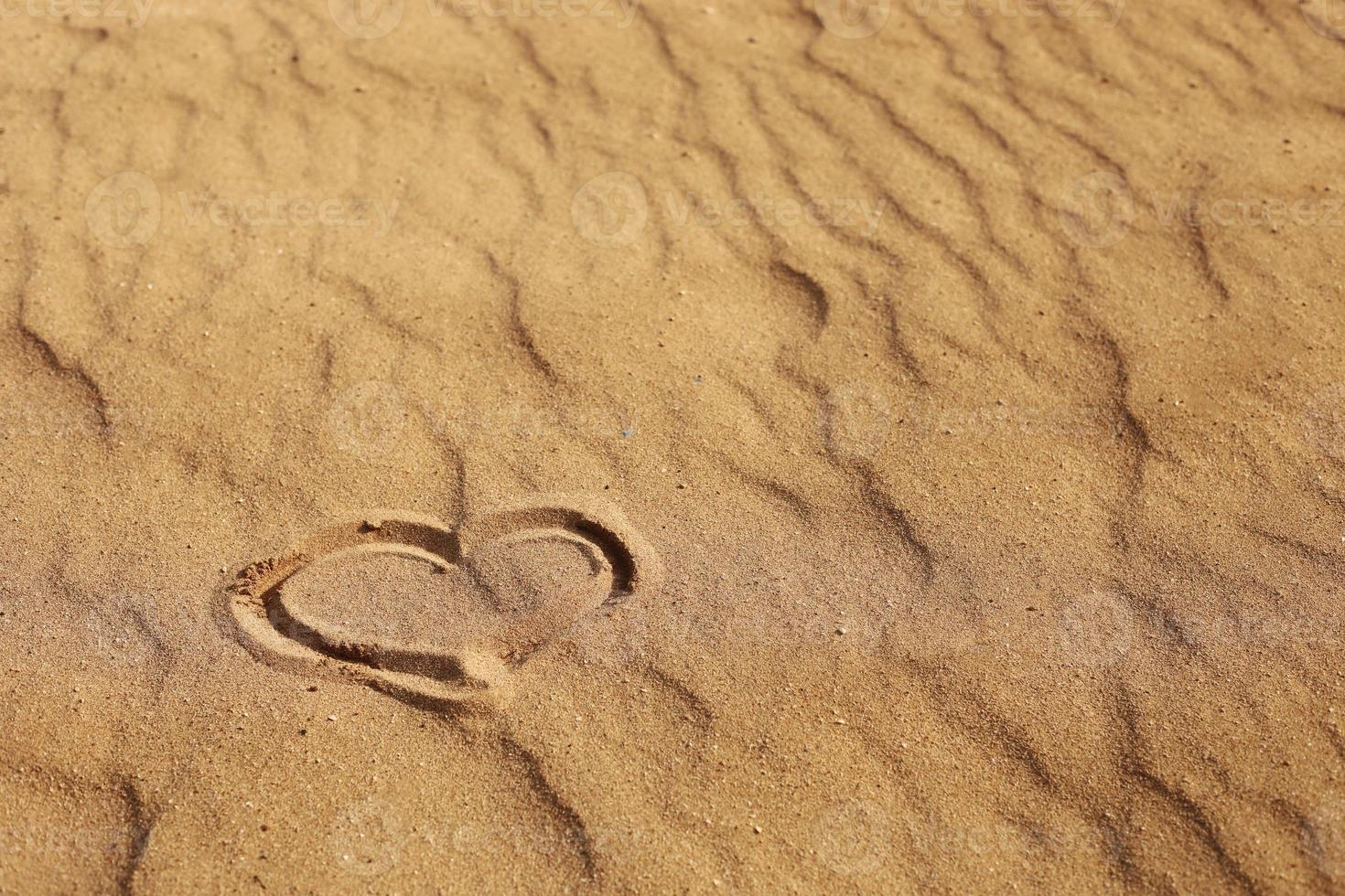 cuore disegnato sulla sabbia, concetto di amore. rilassarsi sulla spiaggia di sabbia. copia spazio. San Valentino su una spiaggia assolata foto