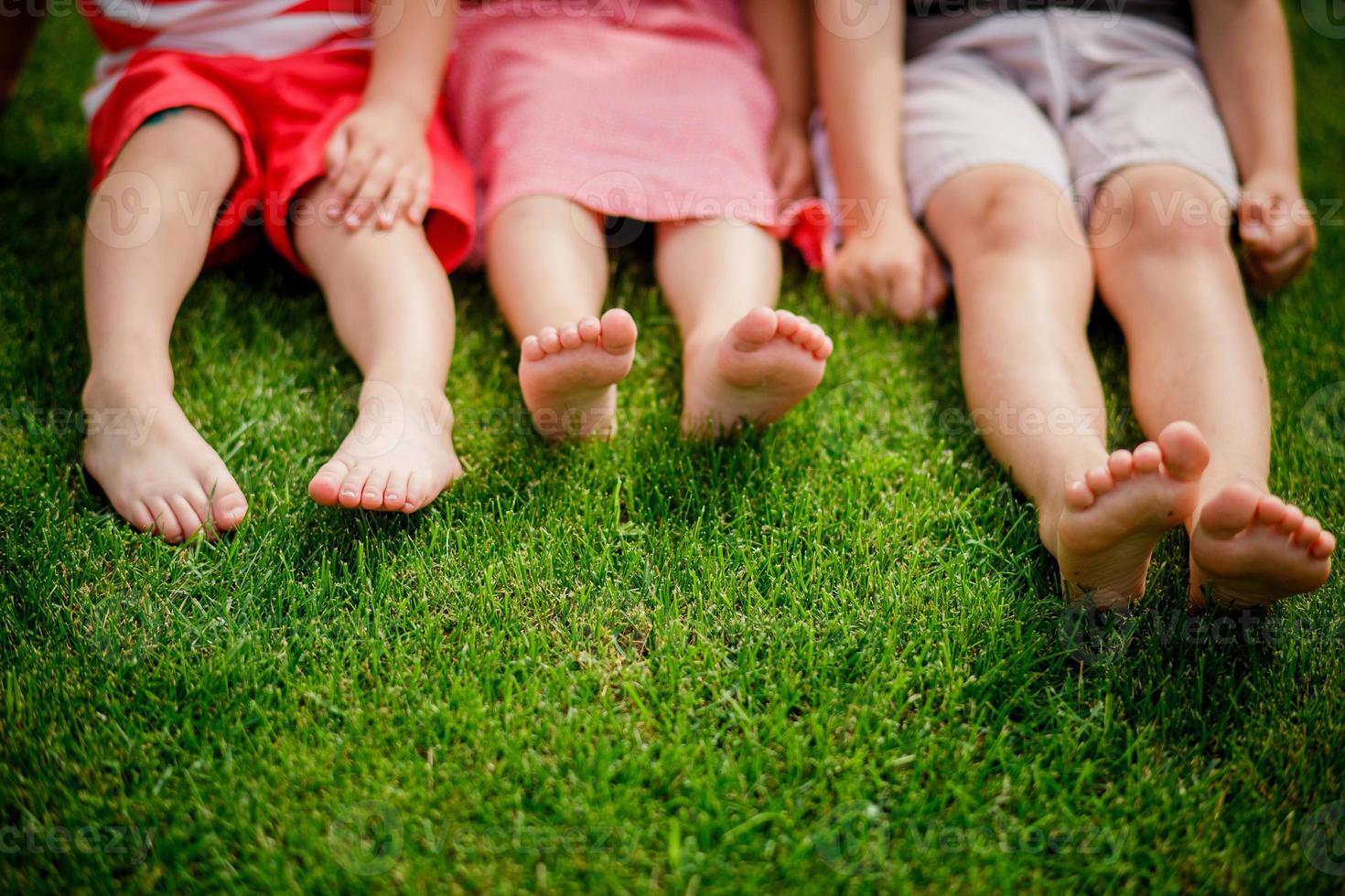 gambe nude di bambine che si siedono sull'erba. foto