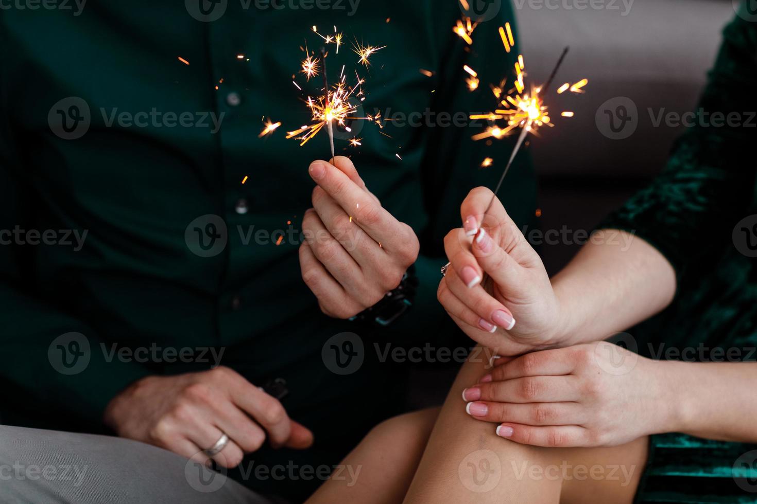 mani maschili e femminili che tengono le luci accese del Bengala. bella giovane famiglia felice che celebra il Natale insieme. coppia che tiene le luci del Bengala. foto